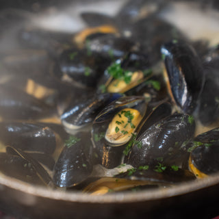 Mussels in a pan with a creamy sauce and herbs